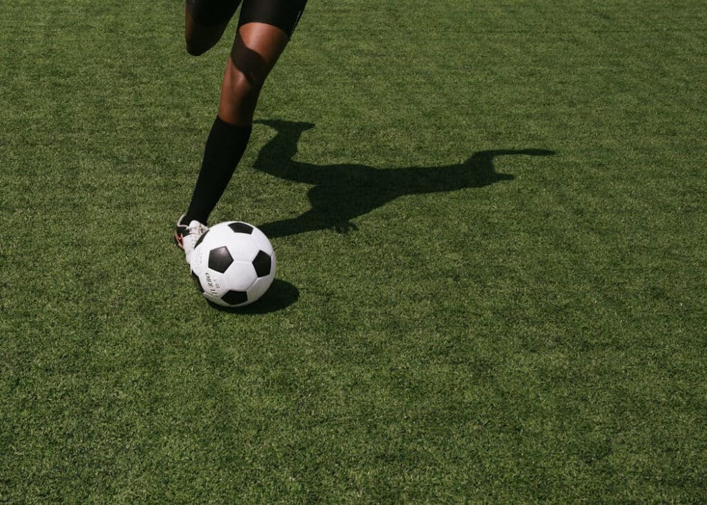 jugador de futbol en campo verde controlando balón con pie derecho