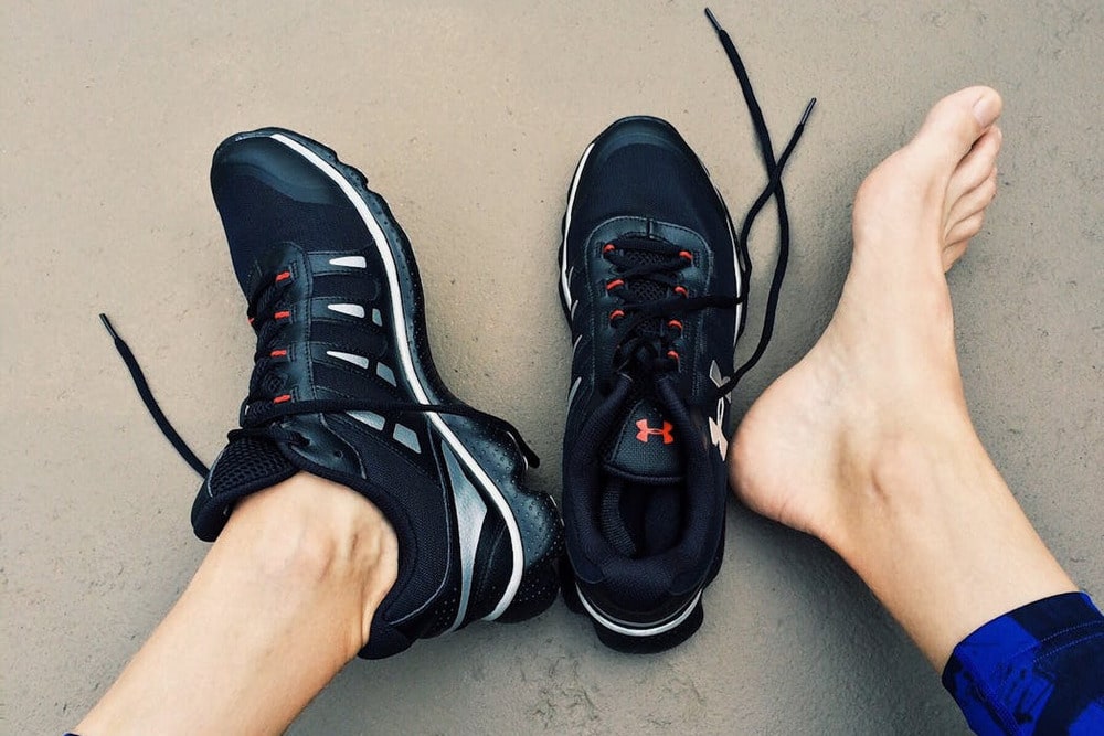 pies de persona con zapatillas deportivas y pie descalzo sobre piso exterior